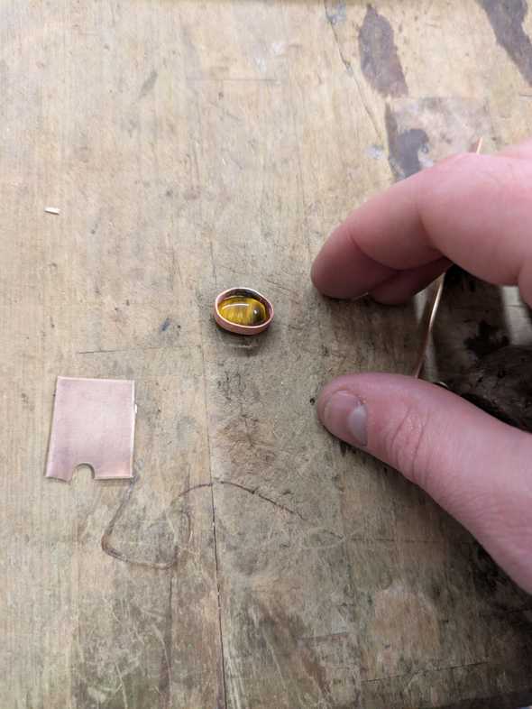 a tigers eye stone with a strip of brass around it