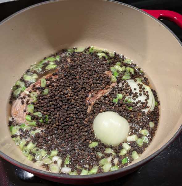 soup in a dutch oven covered by a healthy layer of peppercorns