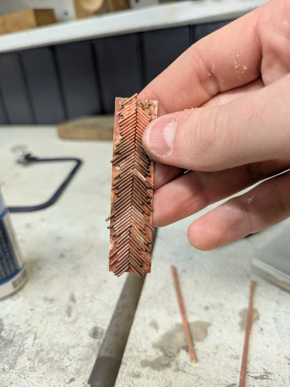 a strip of annealed brass wire in a herringbone pattern on a backing plate