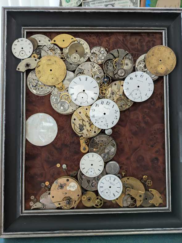 a frame with walnut burl veneer in the background and watch pieces arranged in the shape of a tree